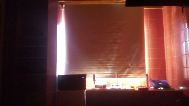 A room with a large window, a flat-screen TV, and a table with various items.