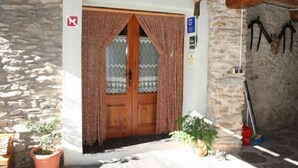 A stone building with a wooden door, a small porch, and a potted plant. - Rural house (full rental) El Racó de Cal Maró for 10 persons (Montferrer i Castellbò)