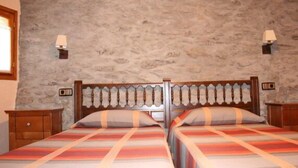 A double bed with a striped bedspread, a wooden headboard, and two bedside tables with lamps. - Rural house (full rental) El Racó de Cal Maró for 10 persons (Montferrer i Castellbò)