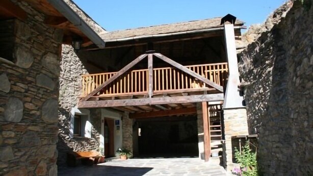 A stone building with a wooden balcony and a stone staircase leading to a covered entrance. - Rural house (full rental) El Racó de Cal Maró for 10 persons (Montferrer i Castellbò)