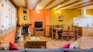 A cozy living room with a fireplace, wooden furniture, and a television. - Rural apartment L'Abiseu for 4 people (Villablino)