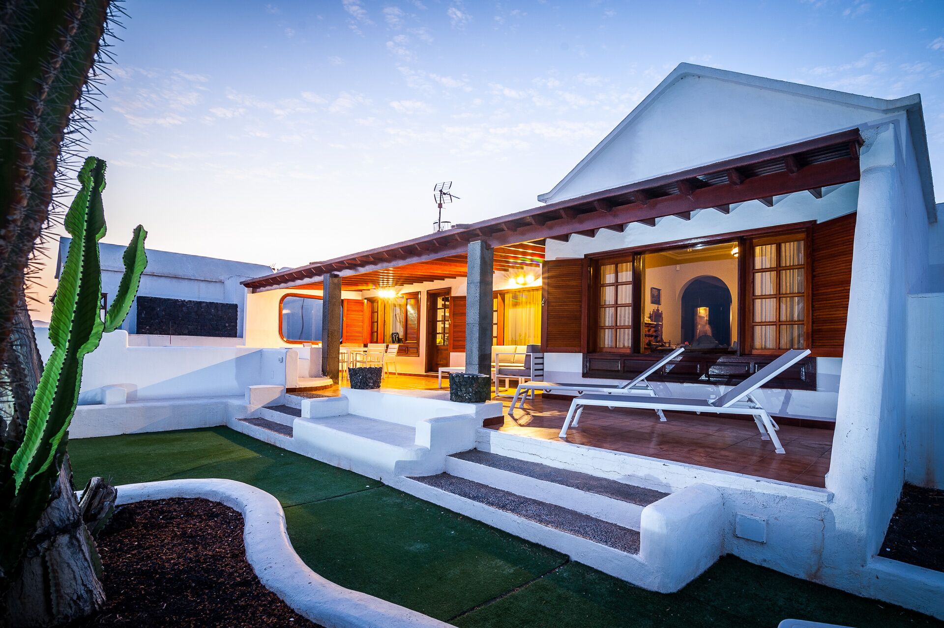 A modern house with a patio, a covered seating area, and a well-maintained lawn.