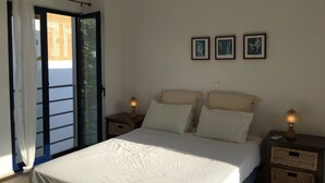 A bedroom with a bed, two bedside tables, a window with curtains, and three framed pictures on the wall. - Island-style 3 bedroom house!  (Rethymno)