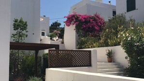 A modern outdoor area with a pergola, steps leading to a white building, and various plants and flowers. - Island-style 3 bedroom house!  (Rethymno)