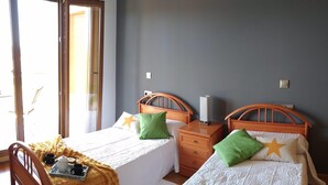 A room with two beds, wooden headboards, and a window with blinds. - Beach, valley and relaxation (Pontevedra)