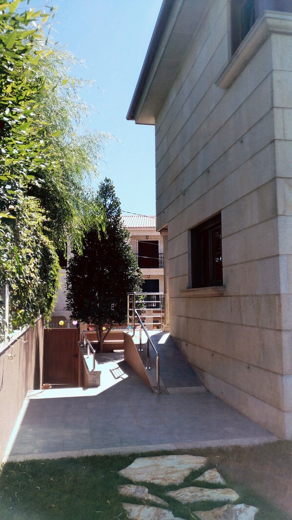 A courtyard with a stone building, a wooden fence, and a tree. - Beach, valley and relaxation (Pontevedra)