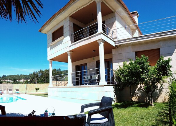 A two-story house with a balcony, a swimming pool, and outdoor furniture. - Beach, valley and relaxation (Pontevedra)