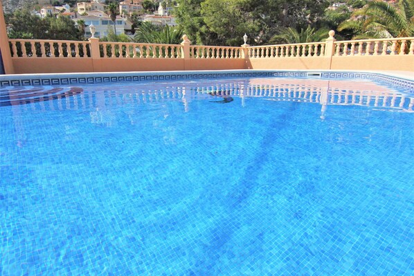 Piscina azul límpida, com borda revestida em azulejo e balaustrada.