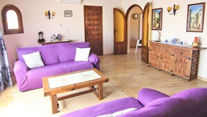 A room with a purple sofa, wooden cabinet, and a wooden coffee table.