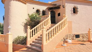 A building with a beige exterior, a stone base, and a staircase with a balustrade.