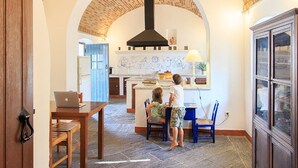 Ein Innenraum mit Backstein-Decke, einer zentralen Kücheninsel und einem Essbereich mit zwei Kindern.