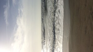 Een strand met golven en een heldere lucht.