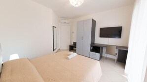 Une chambre à coucher comprenant un lit, un bureau, une chaise, une télévision et une armoire.