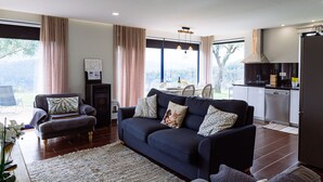 A modern living room with a dark blue sofa, a small armchair, and a dining area with a table and chairs. - Entire house for 5 people, private pool, pets accepted. Fully equipped. (Cabeceira de Basto)