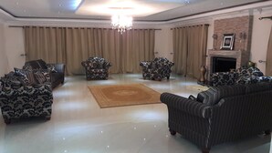 Un salon spacieux, agrémenté de canapés à motifs, d’un tapis central et d’un lustre.
