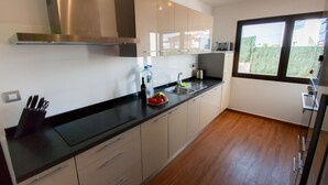 A modern kitchen with a black countertop, stainless steel range hood, and a window providing a view of the outdoors. - Villa Anna - Beautiful exclusive Villa with pool  (Castillo Caleta de Fuste)