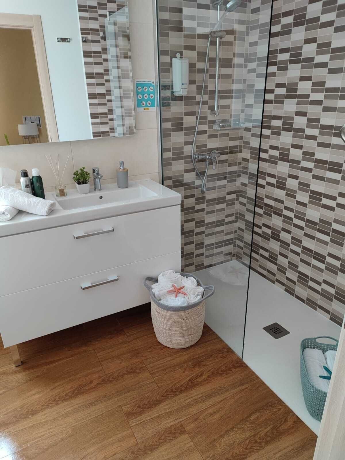 Un baño moderno con tocador blanco, cabina de ducha de vidrio y salpicadero de azulejos.