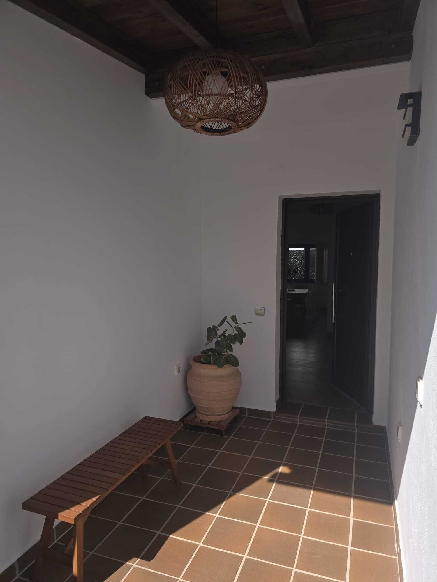 Ein Korridor mit einer Bank, einem Blumentopf und einer gewebten Deckenleuchte.