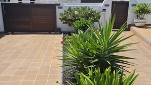 A courtyard with a tiled floor, a metal gate, and a potted plant.