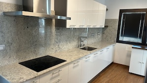 A modern kitchen with granite countertops, stainless steel appliances, and white cabinetry.