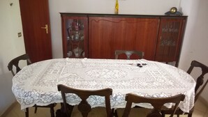 A round dining table with a lace tablecloth, surrounded by wooden chairs.