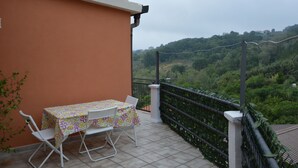 A balcony with a table and chairs, overlooking a lush green landscape.