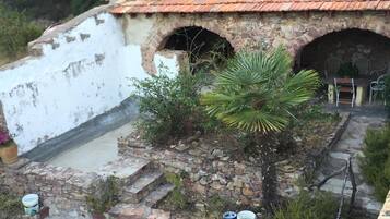 Un patio rústico al aire libre con suelo de piedra, una mesita y sillas.