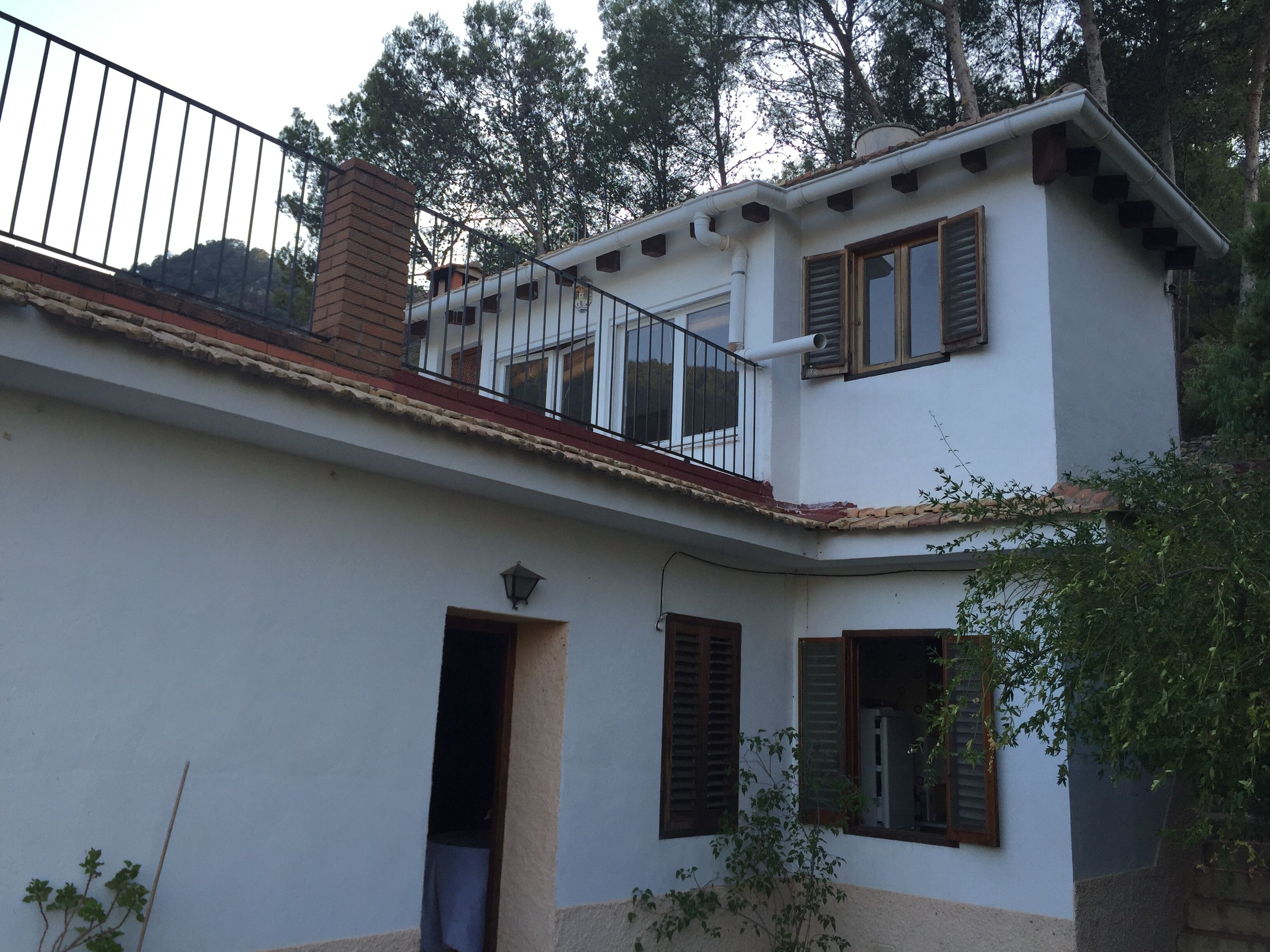 Una casa de dos pisos con un balcón, una chimenea y una puerta que da a un garaje.