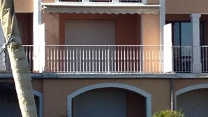 A two-story building with a brown facade, white trim, and a tiled roof. There are balconies with white railings and a garage door. - Romance in Port Grimaud 2p with a/c, parking + private wifi (Grimaud)