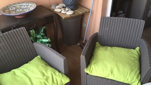 Two wicker chairs with green cushions, a small table with a decorative plate, and a potted plant. - Romance in Port Grimaud 2p with a/c, parking + private wifi (Grimaud)