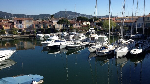 A marina with multiple boats docked, surrounded by residential buildings and hills in the background. - Romance in Port Grimaud 2p with a/c, parking + private wifi (Grimaud)