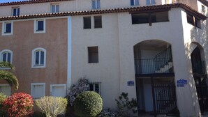 A multi-story building with a beige facade, multiple windows, and a central entrance with a staircase. - Romance in Port Grimaud 2p with a/c, parking + private wifi (Grimaud)