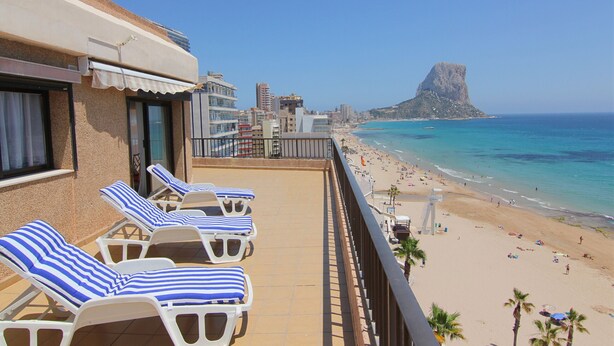 Ein Balkon mit Liegestühlen mit Blick auf einen Strand.