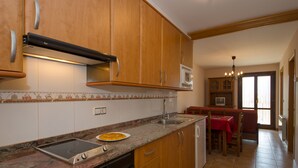 Une cuisine avec des meubles de rangement en bois, un four à micro-ondes encastré, une cuisinière et un lave-vaisselle.