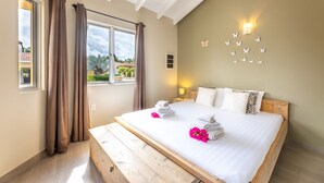 A bedroom with a large bed, curtains, a wall-mounted light, and a view of the outside.