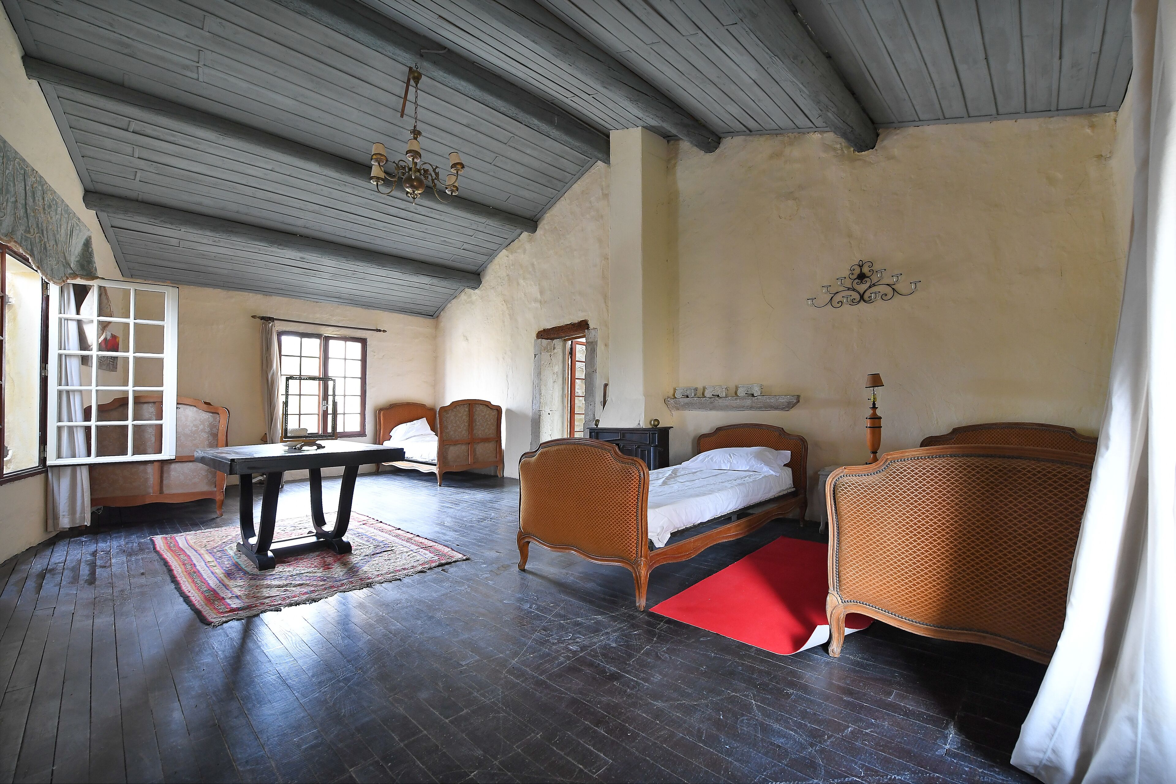 Una stanza con pavimento in legno, un letto con testiera, un tavolo e una sedia.