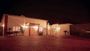 A building with a covered entrance, a stone wall, and a paved area.