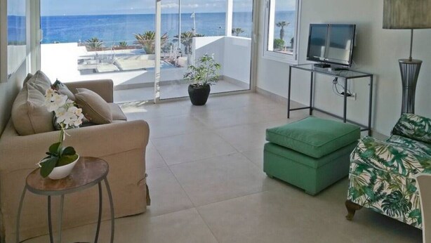 A spacious living room with a large sliding glass door leading to a balcony overlooking the sea. - DORAMAS APARTMENT, Tias (Puerto del Carmen, Tias)