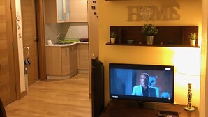 A living room with a TV, wooden cabinets, a fireplace, and a kitchen in the background. - Central Luxury Suite. Parking Included (Vigo)