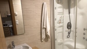 A bathroom with a sink, mirror, towel rack, and a glass-enclosed shower. - Central Luxury Suite. Parking Included (Vigo)