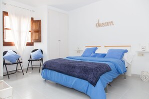 Un dormitorio con cama, dos sillas, una ventana con cortinas, una puerta de madera y una pared con la palabra 'dream' escrita.