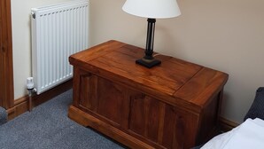 Une pièce avec une table de chevet en bois, un radiateur blanc et un tapis gris.