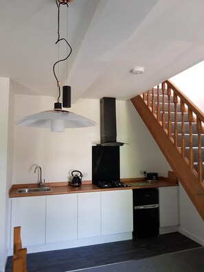 Een kleine keuken met een inbouwfornuis, een spoelbak en een waterkoker.