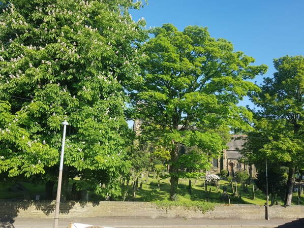 Een begraafplaats met bomen en een stenen gebouw op de achtergrond.
