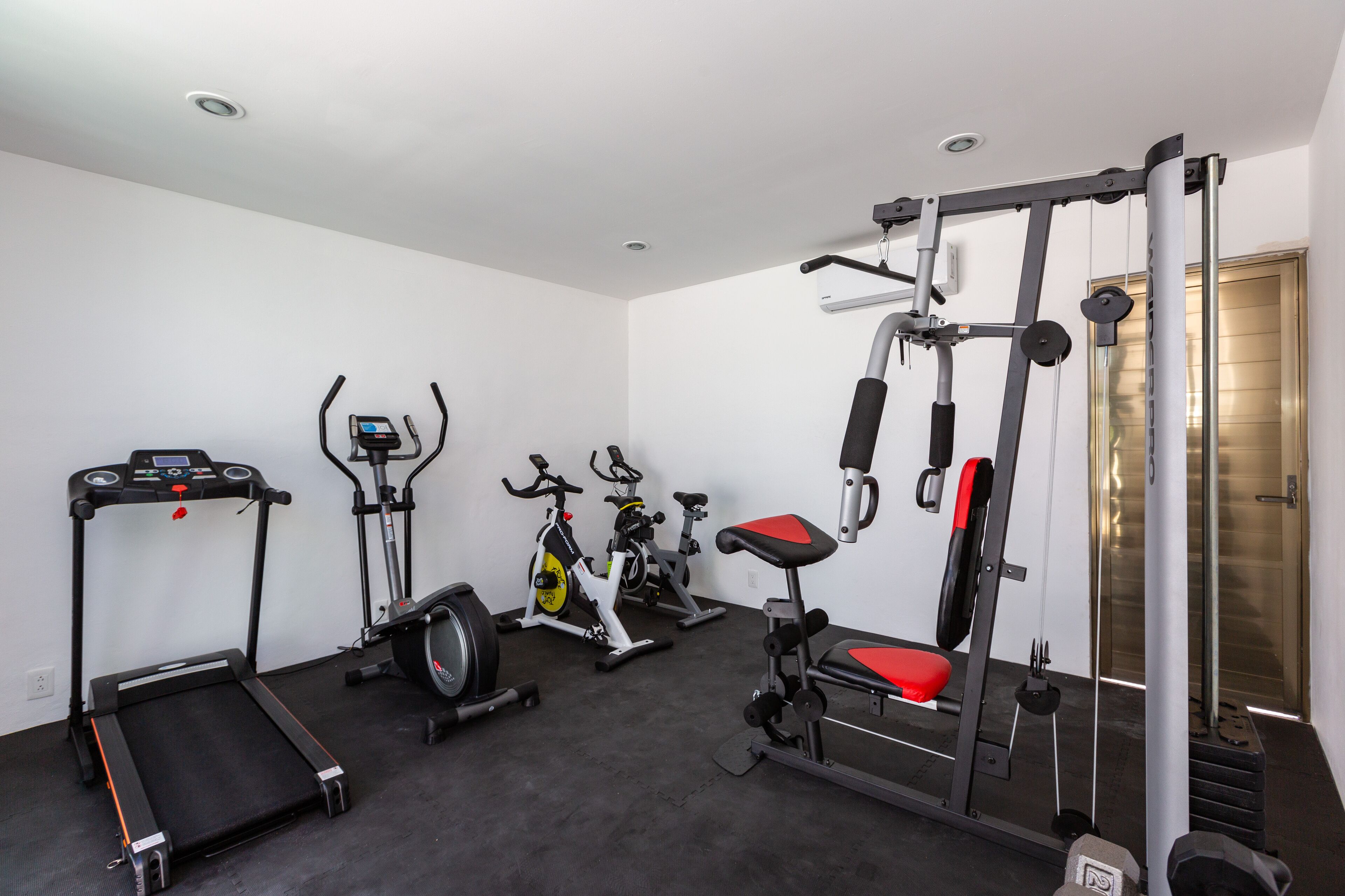 A gym with treadmills, stationary bikes, and a weight bench.