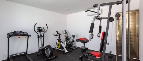 A gym with treadmills, stationary bikes, and a weight bench.