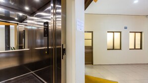 An elevator interior with stainless steel doors and a control panel.