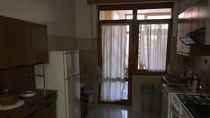 A kitchen with wooden cabinets, a refrigerator, a stove, and a sink. - Anna Apartment- Villaputzu center Apartment (Villaputzu)