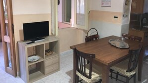 A dining area with a wooden table, chairs, and a television on a stand. - Anna Apartment- Villaputzu center Apartment (Villaputzu)