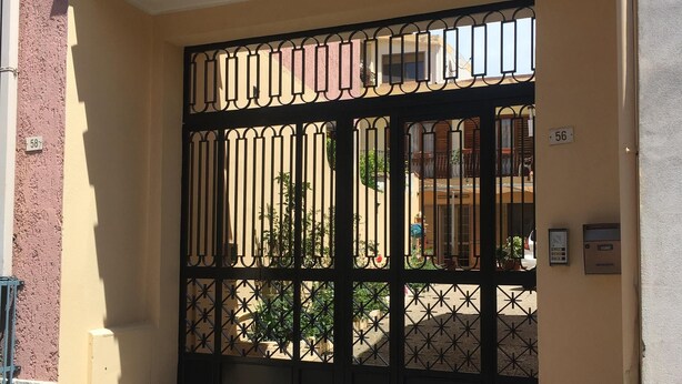 A gated entrance with a metal gate and a number plate. - Anna Apartment- Villaputzu center Apartment (Villaputzu)
